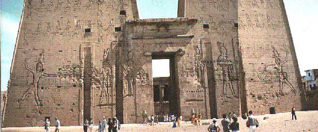 The First Pylon of the Temple of Horus at Edfu, a large structure more than 4 stories tall with huge reliefs of the Pharaoh carved into it.